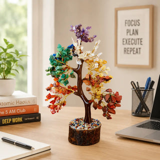 7 Chakra crystal tree displayed on a work desk beside books and laptop
