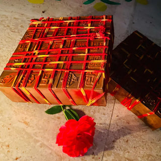 Two Garbha Manjusha copper boxes wrapped in red and yellow thread with rose, ready for foundation installation